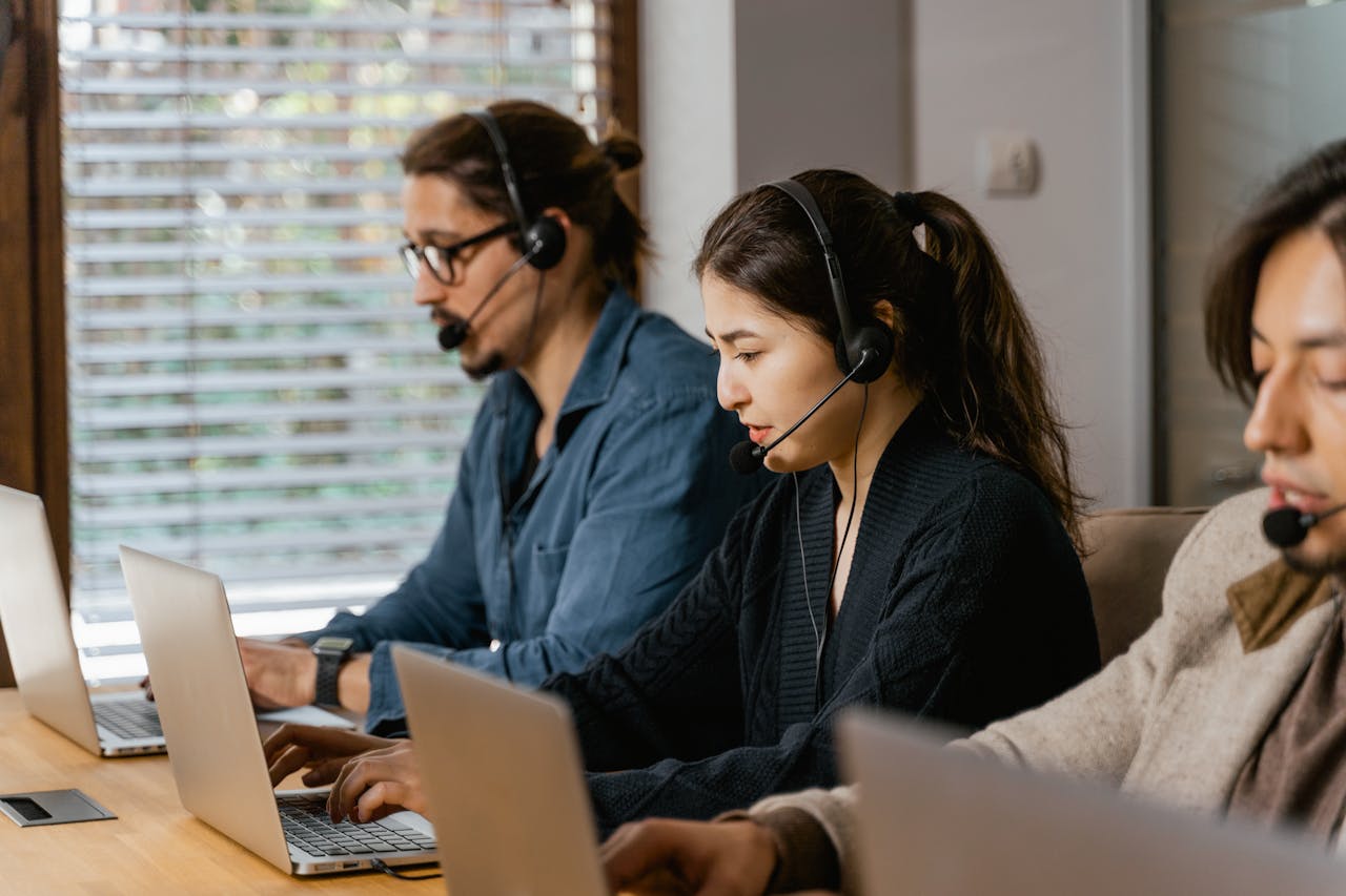 Team of professionals in a call center providing customer support using laptops and headsets.